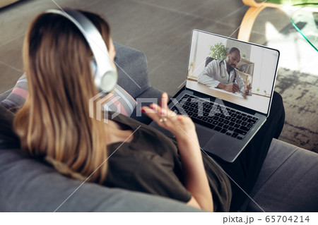 Young woman getting online medical help and advice during videocall with doctor checking symtoms aand explaining the drug's reciepes Young woman getting online medical help and advice during videocall with doctor checking symtoms aand explaining the drug's reciepes 65704214