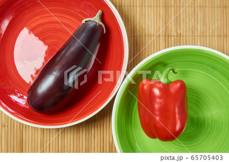 purple eggplant on a red plate and red bell pepper 65705403