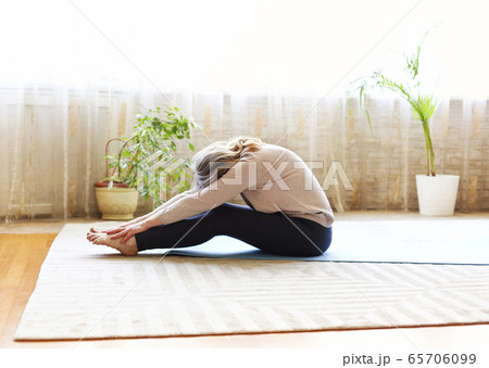 Mature woman stretching body on floor 65706099