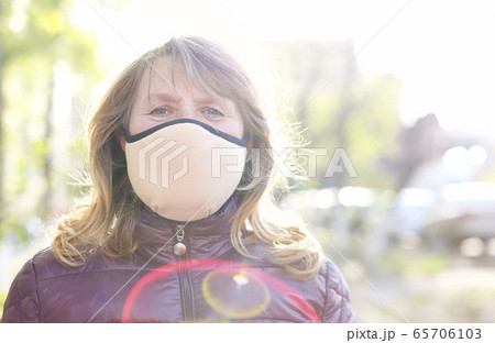 Happy older woman in medical mask outdoors 65706103