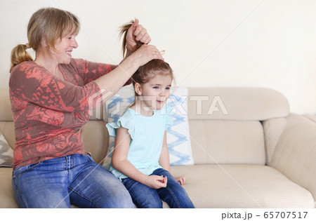 Grandmother doing hair of cute granddaughter Grandmother doing hair of cute granddaughter 65707517