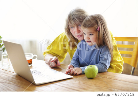 Grandmother and granddaughter using laptop 65707518