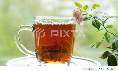 Pouring the tea with leaves of currant, lemon balm, mint, raspberry in a glass cup.Tea party outdoors Pouring the tea with leaves of currant, lemon balm, mint, raspberry in a glass cup.Tea party outdoors 65708367