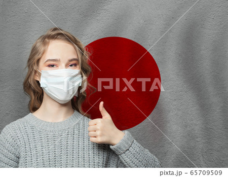 Happy woman in face mask holding thumb up Happy woman in face mask holding thumb up 65709509