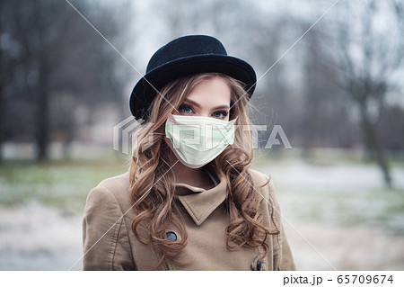Young woman in protective mask outdoors 65709674