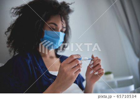 Close up of serious girl that looking at thermometer Close up of serious girl that looking at thermometer 65710534