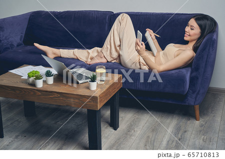 Cheerful young woman using smartphone at home Cheerful young woman using smartphone at home 65710813
