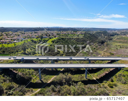 Aerial view of road highway bridge, viaduct supports in the valley among the green hills Aerial view of road highway bridge, viaduct supports in the valley among the green hills 65717407