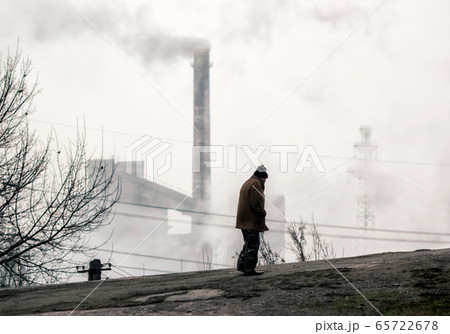 lonely beggar man on the background of smoking chimneys of a factory in Donbass Ukraine 65722678