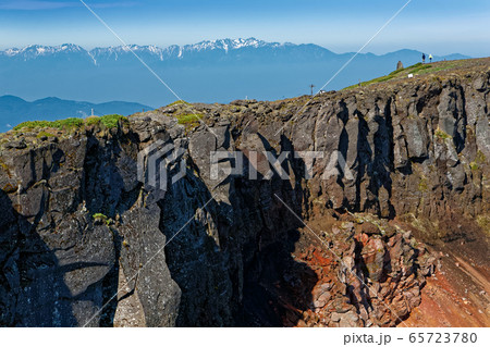 八ヶ岳連峰・硫黄岳山頂の登山者と中央アルプスの山並み 65723780