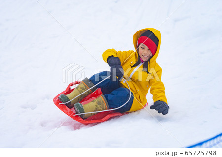 Little Japanese girl is sliding down the snow sled 65725798
