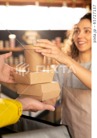 Hand of young waitress in apron holding two carton containers with food 65727137