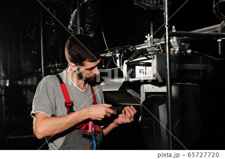 The lighting engineer adjusts the lights on stage behind the scenes The lighting engineer adjusts the lights on stage behind the scenes 65727720