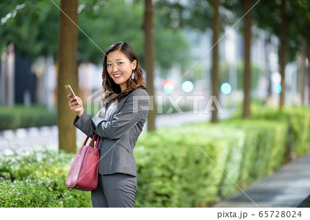 Businesswoman using smartphone outdoors 65728024