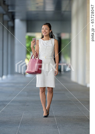 businesswoman walking listening to music via smartphone 65728047