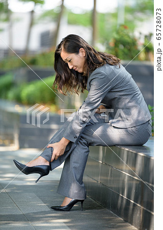 Young woman suffering from leg pain after wearing high heels 65728073