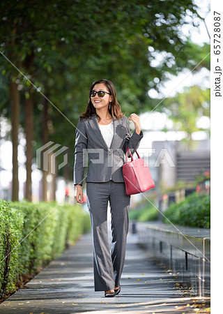 Businesswoman with sunglass walking outdoors 65728087