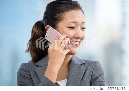 Successful businesswoman making voice call outdoors 65728136