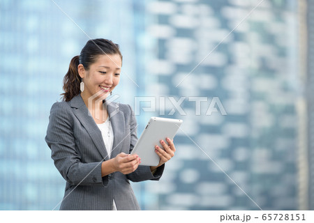 Successful businesswoman using iPad outdoors 65728151