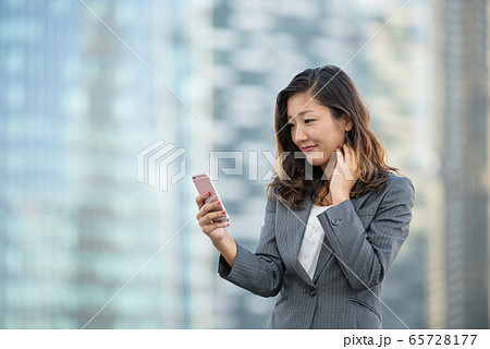 Successful businesswoman using smartphone outdoors 65728177