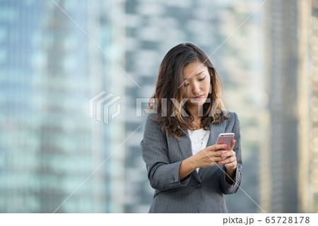 Successful businesswoman using smartphone outdoors 65728178