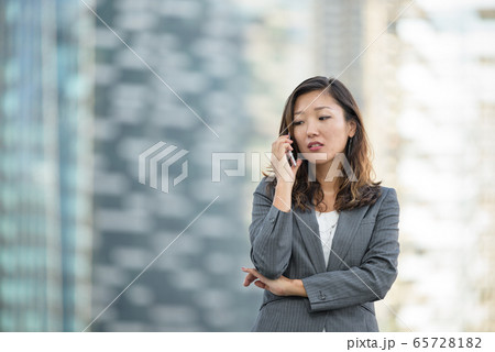 Businesswoman worried look while on voice call, using smartphone, outdoors Businesswoman worried look while on voice call, using smartphone, outdoors 65728182