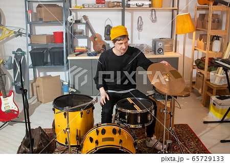 Contemporary young drummer in casualwear sitting in front of drumset Contemporary young drummer in casualwear sitting in front of drumset 65729133