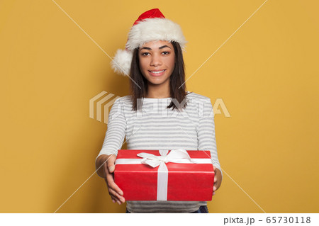 Pretty black woman Santa holding red Christmas box Pretty black woman Santa holding red Christmas box 65730118