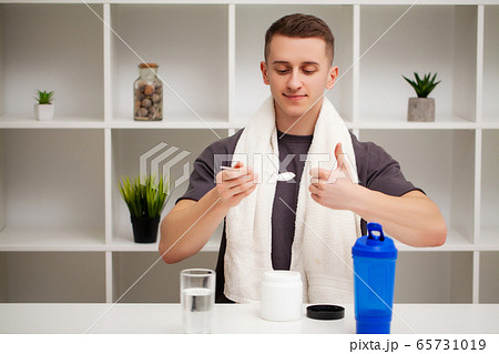 Man prepares a protein shake in the shaker after training. Man prepares a protein shake in the shaker after training. 65731019