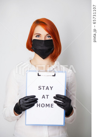 Woman holding blank with inscription stay at home calling for stop spreading covid-19 Woman holding blank with inscription stay at home calling for stop spreading covid-19 65731107