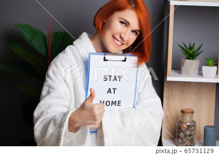 Woman holding blank with inscription stay at home calling for stop spreading covid-19 65731129