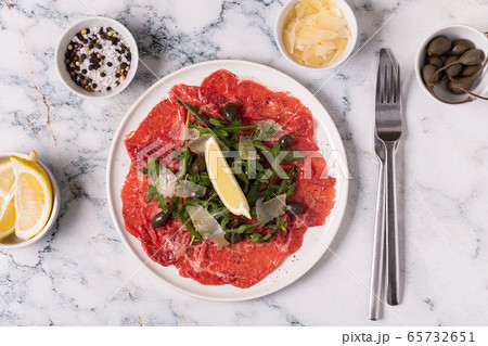 Marbled beef carpaccio with arugula, capers, lemon Marbled beef carpaccio with arugula, capers, lemon 65732651