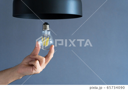 Close-up. A hand changes a light bulb in a stylish 65734090