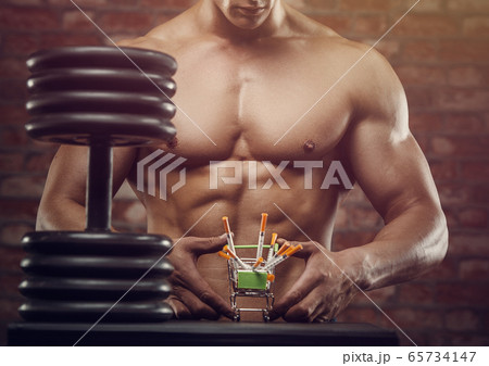 Bodybuilder strong man pumping up abs muscles 65734147