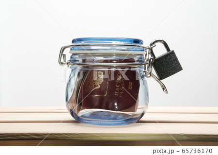Passport in a jar with a lid closed on a lock, white background. Concept of banning visits to other 65736170