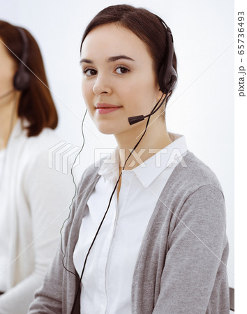Call center. Casual dressed woman working in headset with diverse colleagues at office. Business concept Call center. Casual dressed woman working in headset with diverse colleagues at office. Business concept 65736493