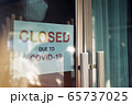 Business office or store shop is closed, bankrupt business due to the effect of novel Coronavirus COVID-19 pandemic. Unidentified person wearing mask hanging closed sign in background on front door. 65737025