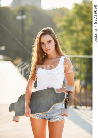 Beautiful girl with skateboard in the hands against the wall 65739099