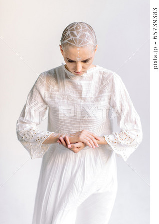 Woman in white bowing head and folding arms 65739383