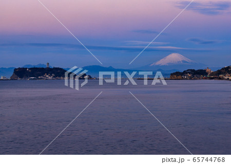 朝焼けに赤く染まる空と富士山、江ノ島、静かな七里ガ浜の海 65744768