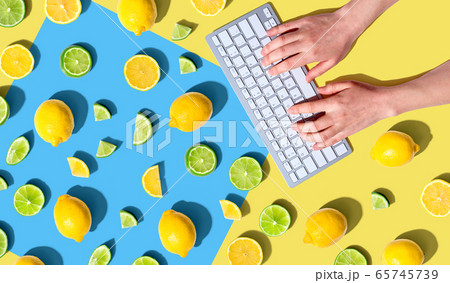 Woman using a computer keyboard with fresh lemons and limes Woman using a computer keyboard with fresh lemons and limes 65745739