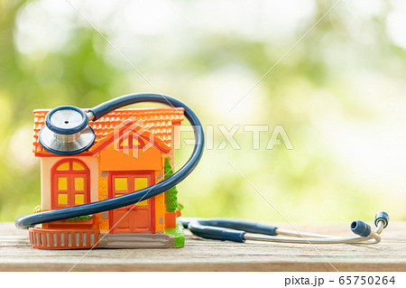 Hand holding blue stethoscope and orange house 65750264