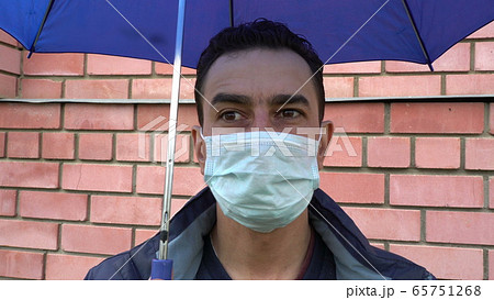 Sad man in mask standing alone under the umbrella, social distance, self isolation, quarantine 65751268