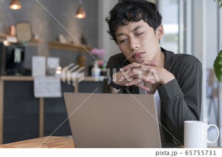 ノートパソコンの前で顔をしかめる男性 65755731