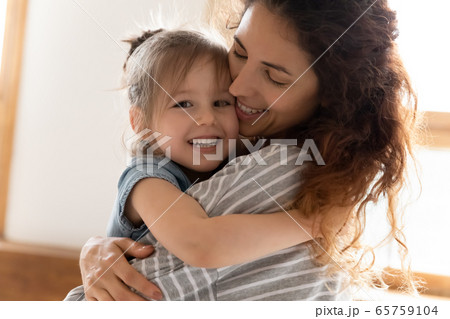 Head shot portrait loving mother and little daughter cuddling Head shot portrait loving mother and little daughter cuddling 65759104