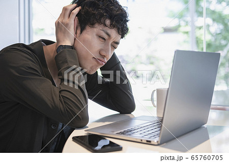 ノートパソコンの前で頭を抱える若い男性 65760705