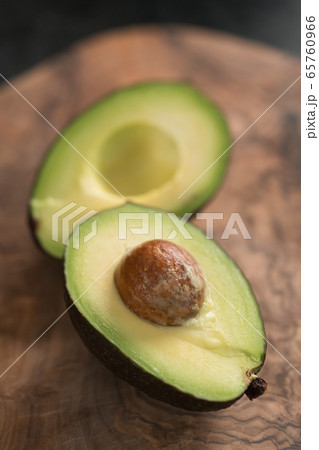 Ripe avocado sliced in halves on olive wood board closeup 65760966