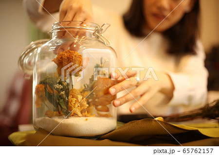 ドライフラワーを瓶に詰める女性の写真素材