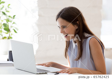 Surprised young woman shocked by message on laptop 65762425