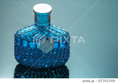 Blue perfume bottle with reflection on black mirror background 65763209